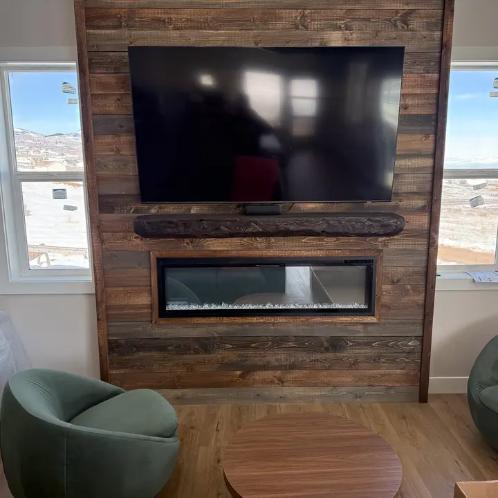 Wood fireplace feature wall around a television and linear fireplace